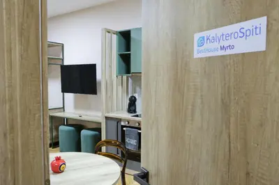 a room with a table and a sign on a wall at Best House Myrto Pasalimani Piraeus in Piraeus