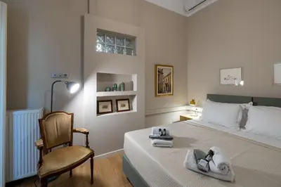 a white bedroom with a bed and a chair at Acropolis slow living apt - Ground floor in Athens