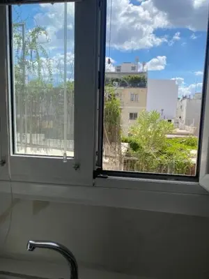 a window above a sink with a view of a city at Neapoli Modern Apartment in Athens