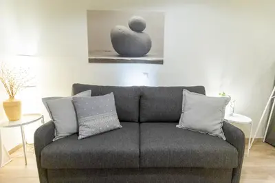 a couch in a living room with a vase on the wall at Eliá Designer Suite - Terraza Lycabettus y Lujo en Mesogeion in Athens