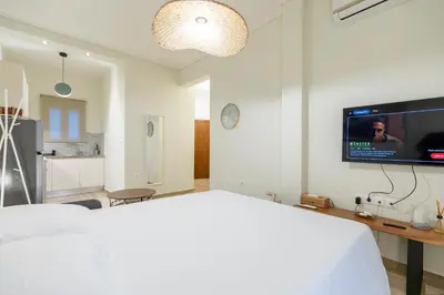 a bedroom with a white bed and a tv on the wall at Eliá Designer Suite - Terraza Lycabettus y Lujo en Mesogeion in Athens