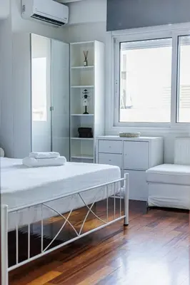 a white bedroom with a bed and a chair at Seaside Grey Pearl Villa in Piraeus