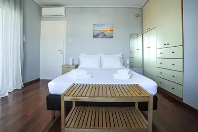 a bedroom with a large white bed and a bench at Seaside Grey Pearl Villa in Piraeus