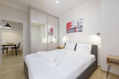 a bedroom with a large white bed and a table at Chic 1-Bedroom Apartment with balcony by WeHost Athens in Athens