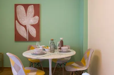 a dining room table with chairs and a table and a painting at Whispering Walls Premium 1 bedroom Apartment in Athens