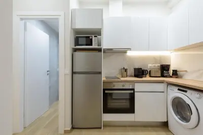 a kitchen with white cabinets and a washer and dryer at Bright 1-Bedroom Apartment by WeHost Athens in Athens