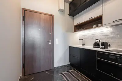 a kitchen with black cabinets and a wooden door at Chic Urban Suite - Parthenon Viewpoint in Athens