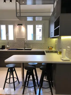 a kitchen with a table and four bar stools at 3 BD apart in the center of Athens 2min from metro in Athens