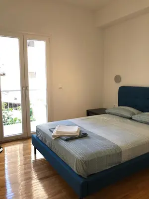 a bedroom with a large bed with a blue head board at 3 BD apart in the center of Athens 2min from metro in Athens