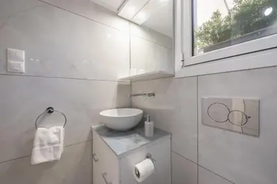 a white bathroom with a sink and a window at Quiet Escape Near Acropolis in Athens
