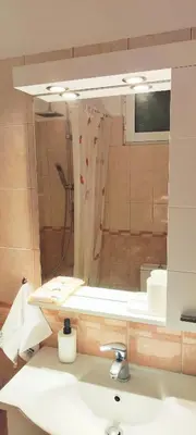 a bathroom with a sink with a mirror and a shower at Zen Apartment in Athens