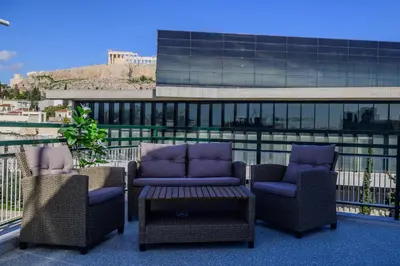 a patio with chairs and a table and a building at Acropolis Touch 7th Wonder View DG in Athens