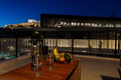 a table with a bowl of fruit and wine glasses on a balcony at Acropolis Touch 7th Wonder View DG in Athens