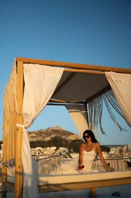 a woman in a white dress sitting on a bed at The Square Hotel by X&N in Athens