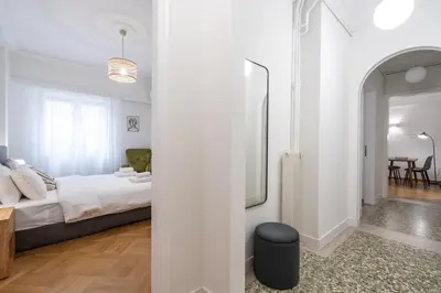 a white bedroom with a bed and a mirror at Modern apartment near Lycabettus hill with balcony in Athens