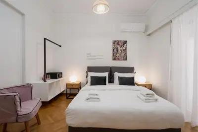 a bedroom with a large white bed and a chair at Modern apartment near Lycabettus hill with balcony in Athens