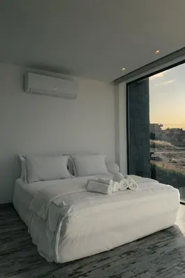 a white bedroom with a large bed and a window at Horizon Luxury Seafront Villa in Vaia
