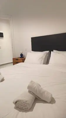 a white bed with white sheets and pillows at The Blue Apartment in Athens