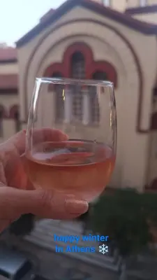 a hand holding a glass of wine in front of a church at The Blue Apartment in Athens