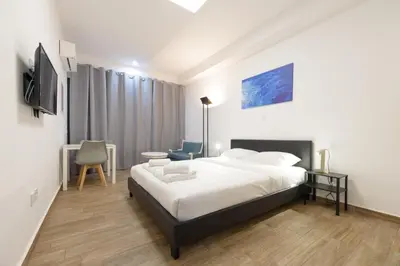 a bedroom with a bed and a desk and a tv at Stylish elevated ground floor studio with yard in Athens