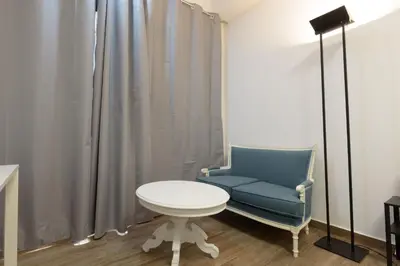 a blue chair and a white table in a room at Stylish elevated ground floor studio with yard in Athens