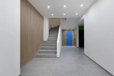 a hallway with stairs and a blue door at Stylish elevated ground floor studio with yard in Athens