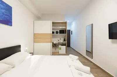 a bedroom with a large white bed with two white chairs at Stylish elevated ground floor studio with yard in Athens