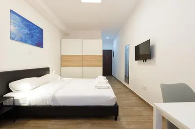a bedroom with a bed and a flat screen tv at Stylish elevated ground floor studio with yard in Athens