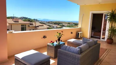 a balcony with wicker furniture and a view of a city at Luxury villa El Verano with private pool in Kalívia Thorikoú