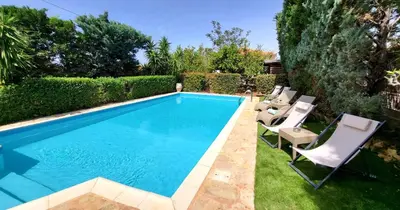 a swimming pool with lounge chairs next to a yard at Luxury villa El Verano with private pool in Kalívia Thorikoú