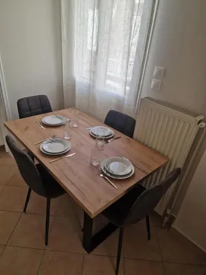 a wooden table with chairs and plates and wine glasses at The Argy Apartment in Athens