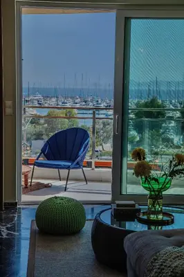 a living room with a blue chair and a large window at Alimos Marina Home - Luxury Corner SeaView Apartment in Athens