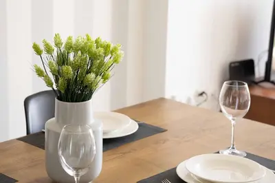 a table with two glasses and a vase with flowers at Urban Comfort near Piraeus Port D3 in Piraeus
