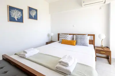 a white bedroom with a bed with towels on it at Urban Comfort near Piraeus Port D3 in Piraeus