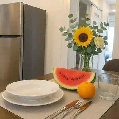 a table with a plate of watermelon and a vase with a sunflower at Lovingly apartment Galatsi 1 in Athens