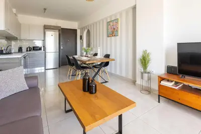 a living room with a table and a kitchen at Modern Stay near Piraeus Port E3 in Piraeus