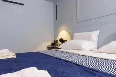 a bed with a blue blanket and white pillows at Sani Suite 7 in Athens