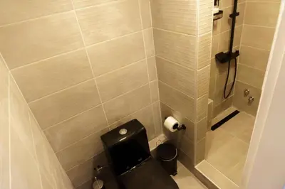a bathroom with a black toilet and a shower at Sani Suite 7 in Athens