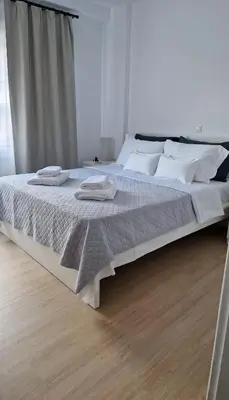 a large bed with white sheets and pillows on it at Cozy apartment in Athens in Athens