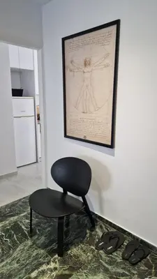 a black chair in a room with a picture and shoes at Cozy apartment in Athens in Athens