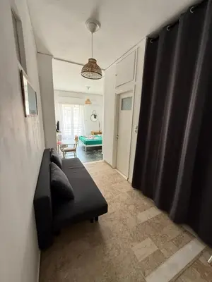 a living room with a black couch and a table at Cósy apartment in Palaiá Fókaia