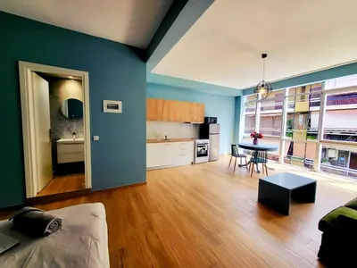 a living room with blue walls and a kitchen with a table at Studios & Shared Roof to Acropolis in Athens