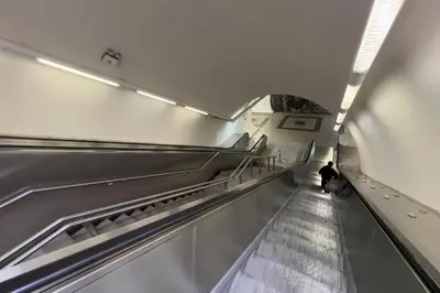 an escalator in a subway station with a man walking down it at Zen Ermou City Center 2 in Athens