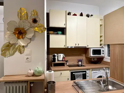 a kitchen with white cabinets and a flower on the wall at Acropolis Gem in Central Athens in Athens