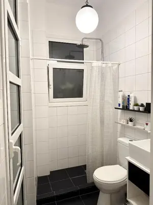 a white bathroom with a toilet and a window at Acropolis Gem in Central Athens in Athens