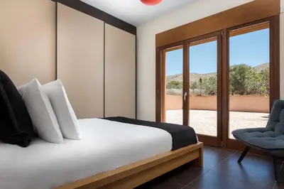 a bedroom with a bed and a chair and a window at Calm Retreat Villa Lagonisi in Kalívia Thorikoú