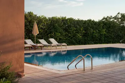 a swimming pool with lounge chairs and an umbrella at Calm Retreat Villa Lagonisi in Kalívia Thorikoú