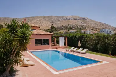 a swimming pool with chairs and a house at Calm Retreat Villa Lagonisi in Kalívia Thorikoú