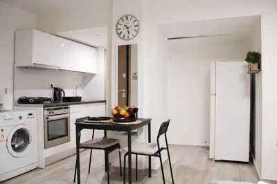 a kitchen with a table and chairs and a clock on the wall at ARIS- King suite on the boulevard in Athens