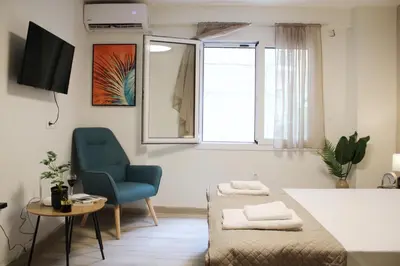 a bedroom with a bed and a blue chair and a window at ARIS- King suite on the boulevard in Athens